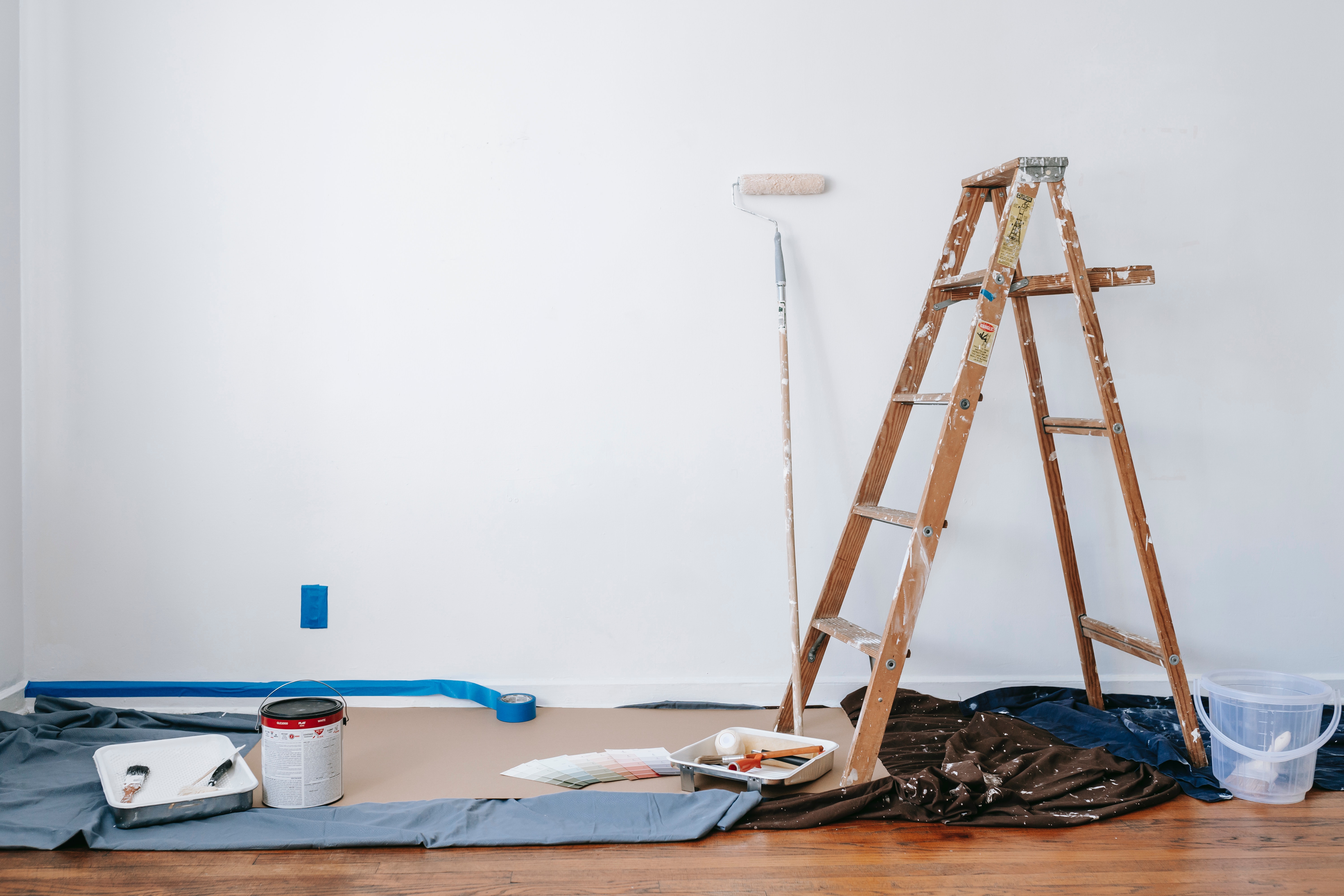 stock photo for painting services showing living room, white wall, painting supplies, and ladder