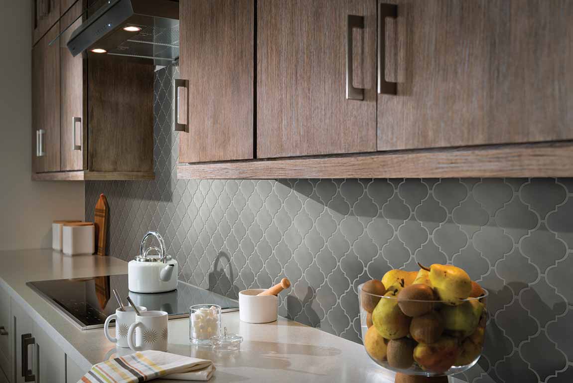 Trending 2020 themed kitchen with dark wood cabinets, white countertops, and grey-green backsplash.